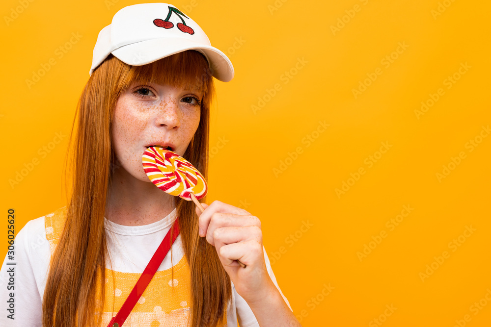 stylish red-haired girl sucks a lollipop over background stylish red-haired girl sucks a lollipop over background