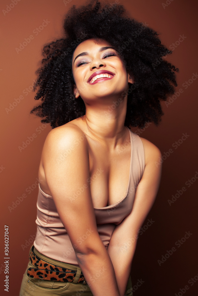 pretty young african american woman with curly hair posing cheerful gesturing on brown background, lifestyle people concept pretty young african american woman with curly hair posing cheerful gesturing on brown background, lifestyle people concept