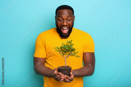 Happy surprised boy hold a small tree ready to be planted. Concept of forestation