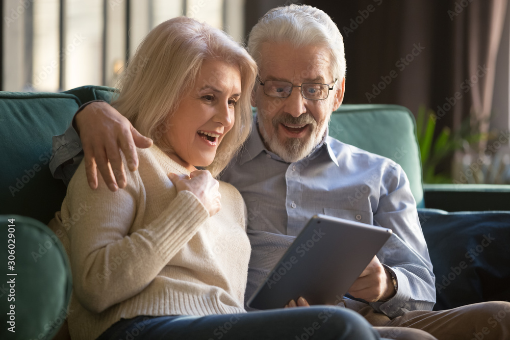 Happy amazed elderly couple looking at digital tablet screen Happy amazed elderly couple looking at digital tablet screen