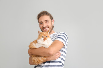 Man with cute cat on light background