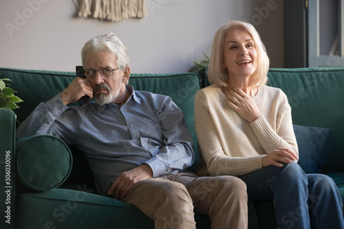 Elderly wife soap opera lover and annoyed husband watching television