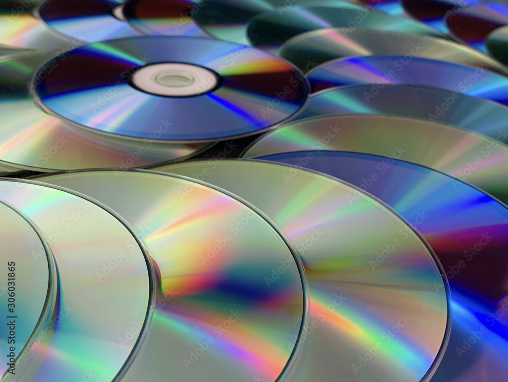 Background texture: a lot of computer disks. Music CDs on a black background, abstraction. Concept: melody, music, melomania. Background texture: a lot of computer disks. Music CDs on a black background, abstraction. Concept: melody, music, melomania.