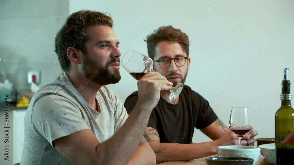 Handsome bearded man talking and drinking red wine. Cheerful friends spending time together. Communication concept Handsome bearded man talking and drinking red wine. Cheerful friends spending time together. Communication concept