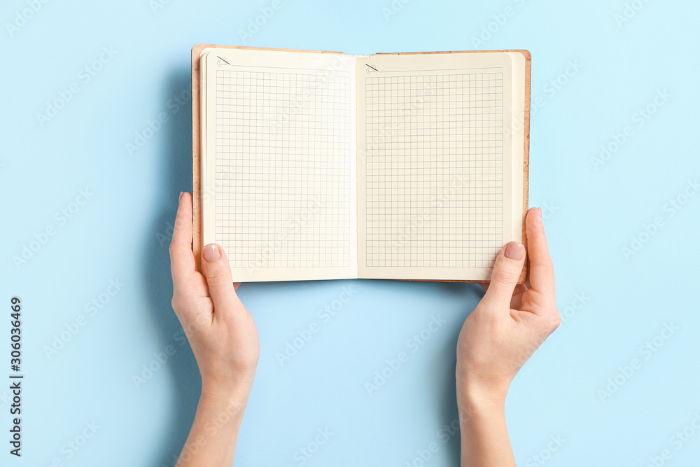 Female hands with blank notebook on color background Female hands with blank notebook on color background