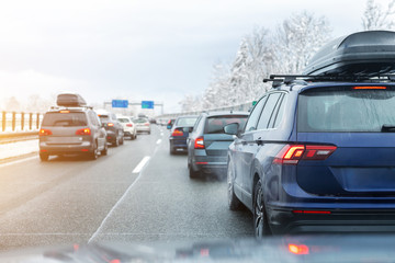 Winter highway with many different cars stucked in traffic jam due to bad weather conditions. Vehicles on wet road after heavy snowstorm and blizzard on cold winter day in Austria near Germany border