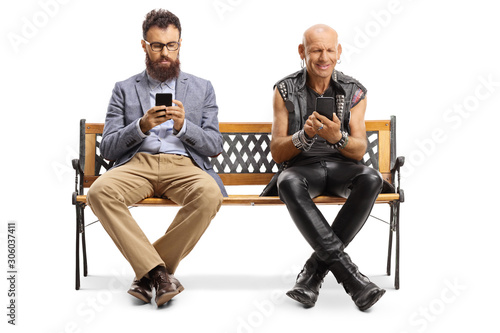 Bearded man and a punker sitting on a bench and typing on mobile phones