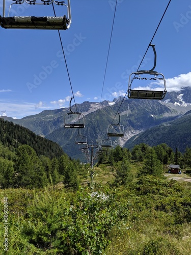 Empty chairlifts in the French Alps during a summer day. Cable car. Forest, trees, rocky mountains.