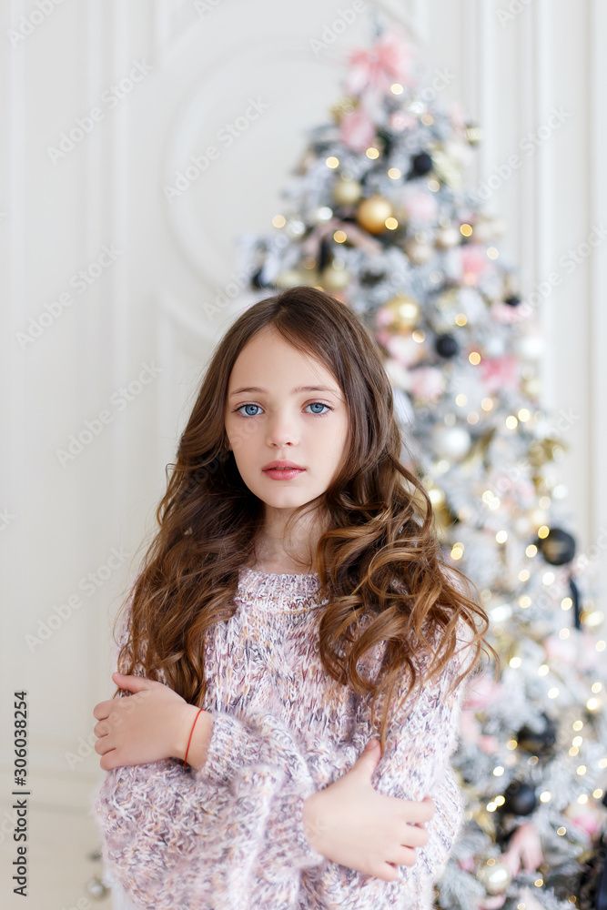 Christmas celebration. Beautiful girl posing near the christmas tree. Christmas miracles Christmas celebration. Beautiful girl posing near the christmas tree. Christmas miracles