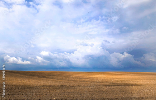 A beautiful field under the blue sky with clouds. The field after the harvest, agricultural landscape