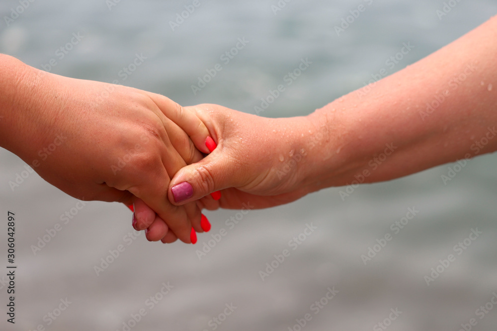 Covered female hands with manicure on a background of the sea. Horizontal, cropped shot, close-up. The concept of friendship and same-sex love. Covered female hands with manicure on a background of the sea. Horizontal, cropped shot, close-up. The concept of friendship and same-sex love.