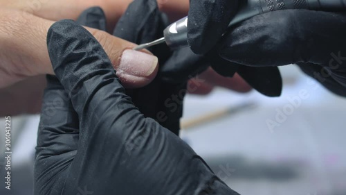 Electric Nail Drill in Manicure Salon.  Female manicurist makes manicure on clients nails.  Nail manicure process in a beauty salon.