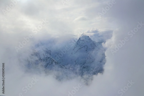 view on snowy mountains peak through clouds