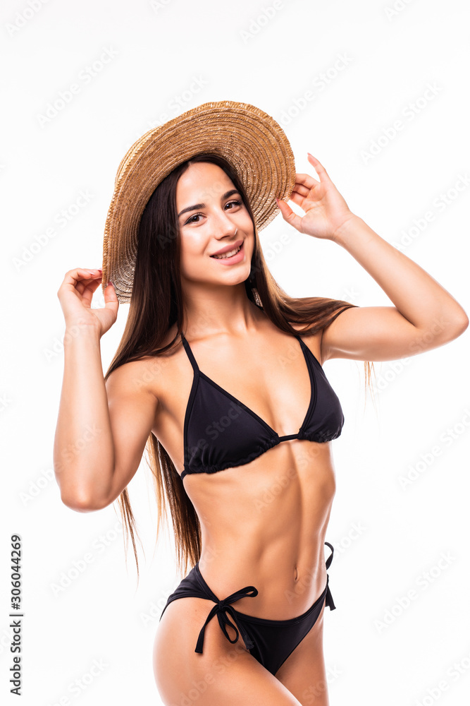 Beauty in hat. Attractive young woman in bikini looking at camera and adjusting her hat while standing isolated on white Beauty in hat. Attractive young woman in bikini looking at camera and adjusting her hat while standing isolated on white