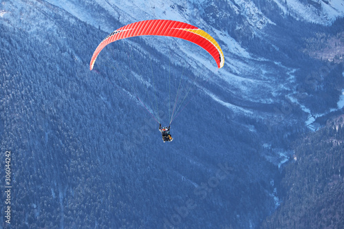 paraplane flying over snowy Caucasus mountains sunny blue sky photo