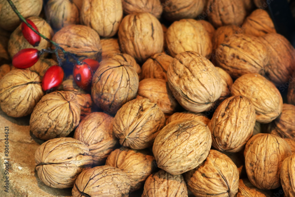 many walnuts with close shell and some red berries - christmas food background many walnuts with close shell and some red berries - christmas food background