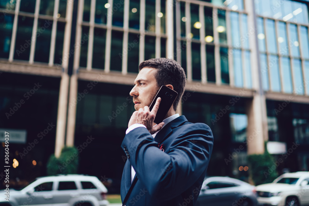 Side view of serious Caucasian man in formal wear making smartphone international conversation discussing business project, intelligent male corporate director using roaming 4g for phoning via mobile Side view of serious Caucasian man in formal wear making smartphone international conversation discussing business project, intelligent male corporate director using roaming 4g for phoning via mobile