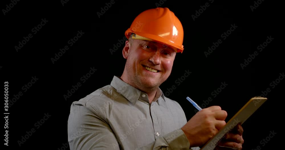 man in orange helmet writes on clipboard paper with blue pen man in orange helmet writes on clipboard paper with blue pen