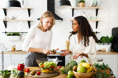 Two women of different nationalities are talking and cooking in the kitchen