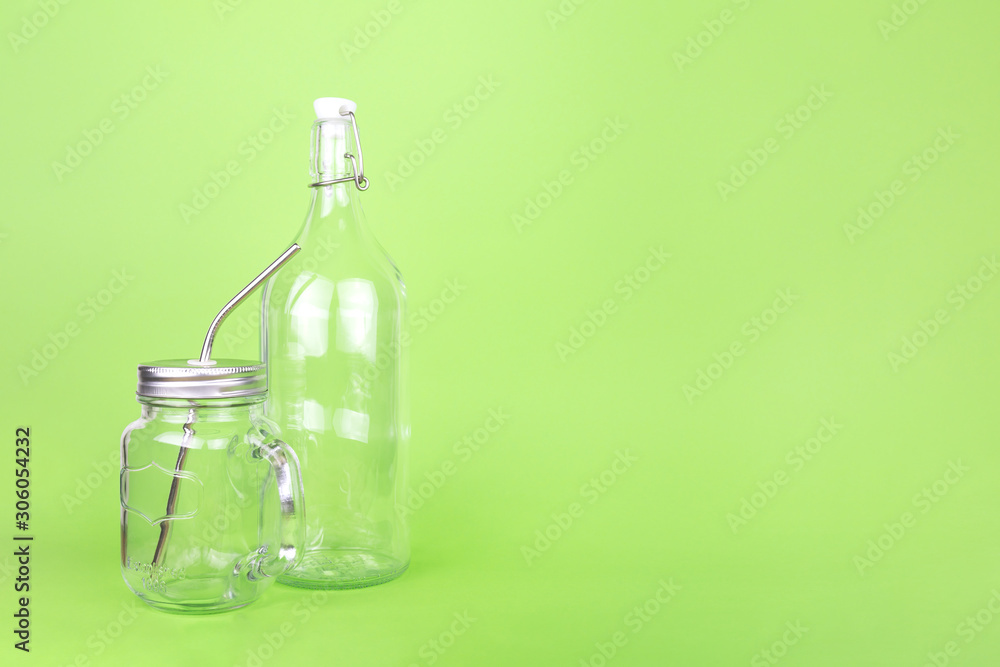 Reusable glass bottle and jar with metal straw on the light green drop, zero waste concept Reusable glass bottle and jar with metal straw on the light green drop, zero waste concept