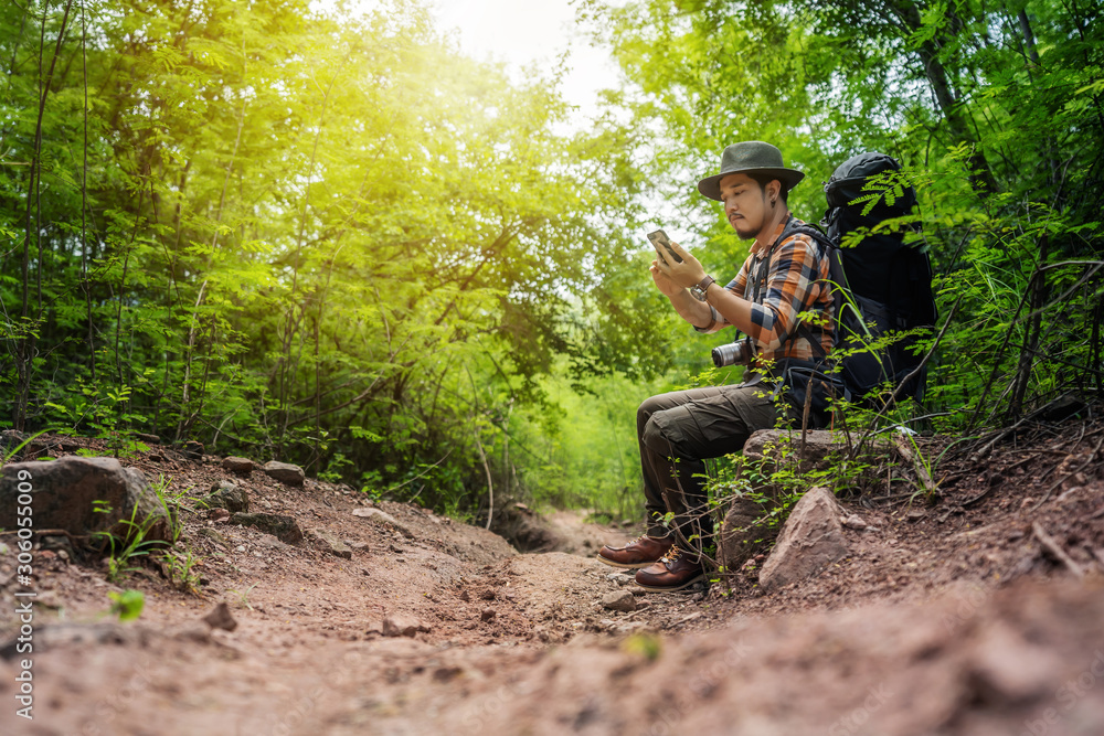 man traveler with backpack using smartphone in the forest man traveler with backpack using smartphone in the forest
