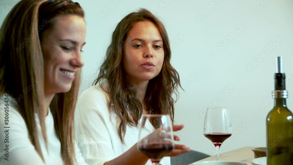 Beautiful brunette woman talking to interlocutor during dinner. Two smiling women sitting at table. Communication concept Beautiful brunette woman talking to interlocutor during dinner. Two smiling women sitting at table. Communication concept