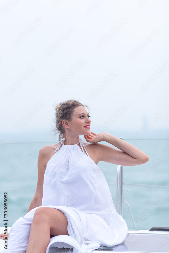 beautiful woman relaxing on a cruise boat wearing white dress