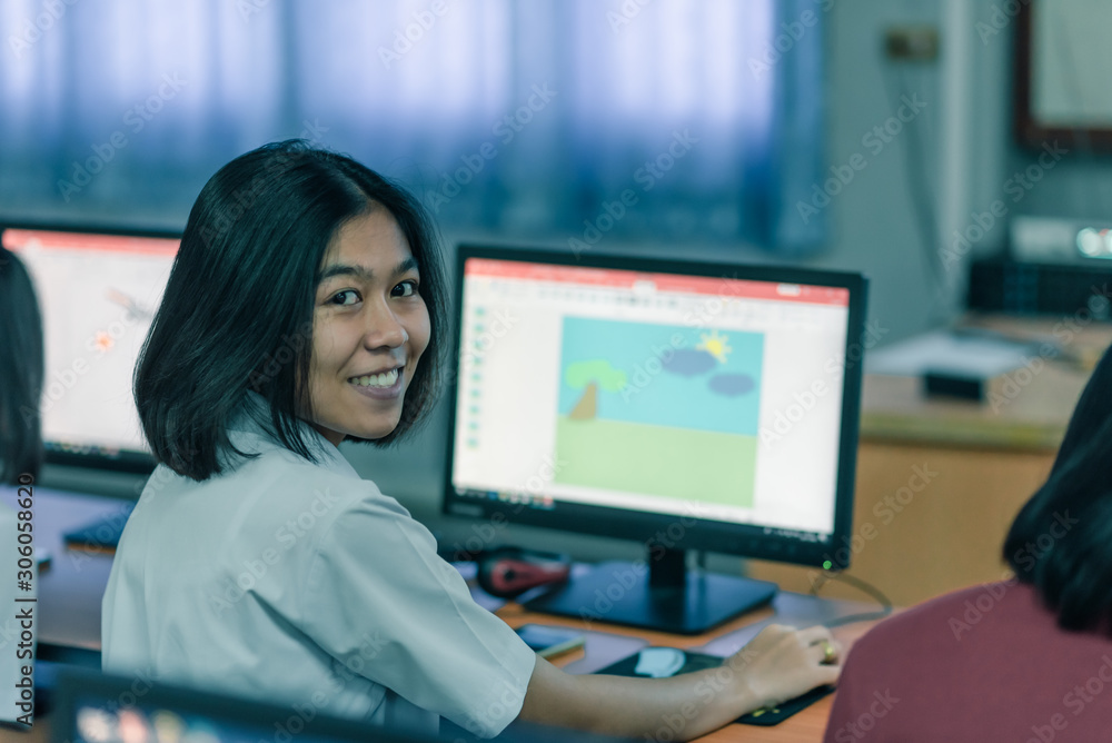 A smiling Asian female high school student in white uniform is learning in computer room. A smiling Asian female high school student in white uniform is learning in computer room.