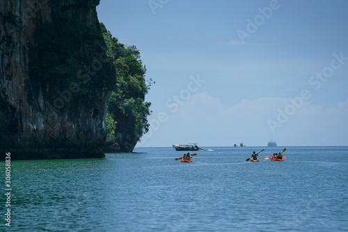 Selective focus on group of travelers canoeing on the surface of sea for touring with seascape and island inbackground photo