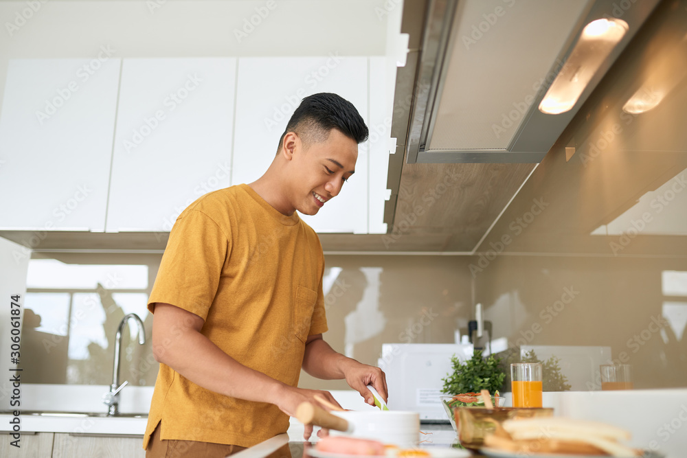 happy young man cutting vegetables in kitchen happy young man cutting vegetables in kitchen