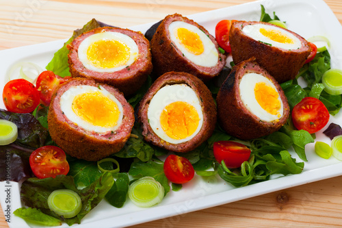 Scotch eggs with tomatoes, greens and leek, traditional Scottish cuisine