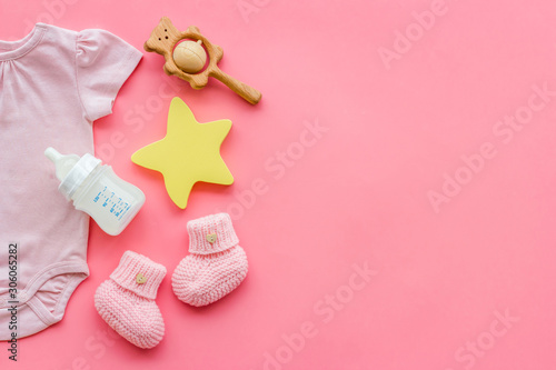 Baby background - pink color. Clothes, booties and accessories for newborn girl on pink table top-down frame copy space