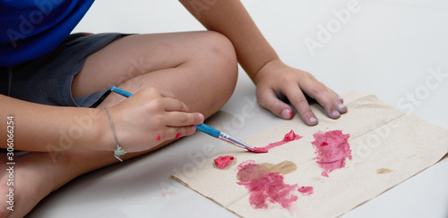Kid hand make art activity with brush and slime coloring on paper on floor