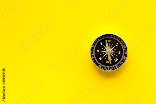 Compass - small and stylish - on yellow background top view copy space