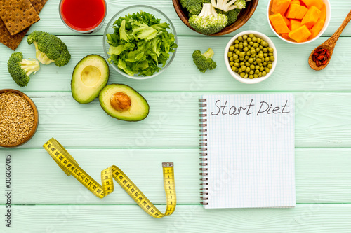 Diet program mockup. Start diet text in notebook near vegetables on green wooden background top view