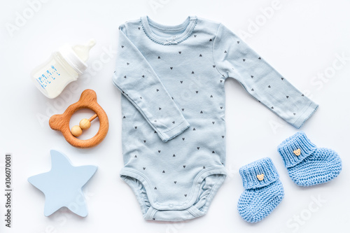 Newborn baby boy set - blue clothes as bodysuit, booties, toys - on white table top-down