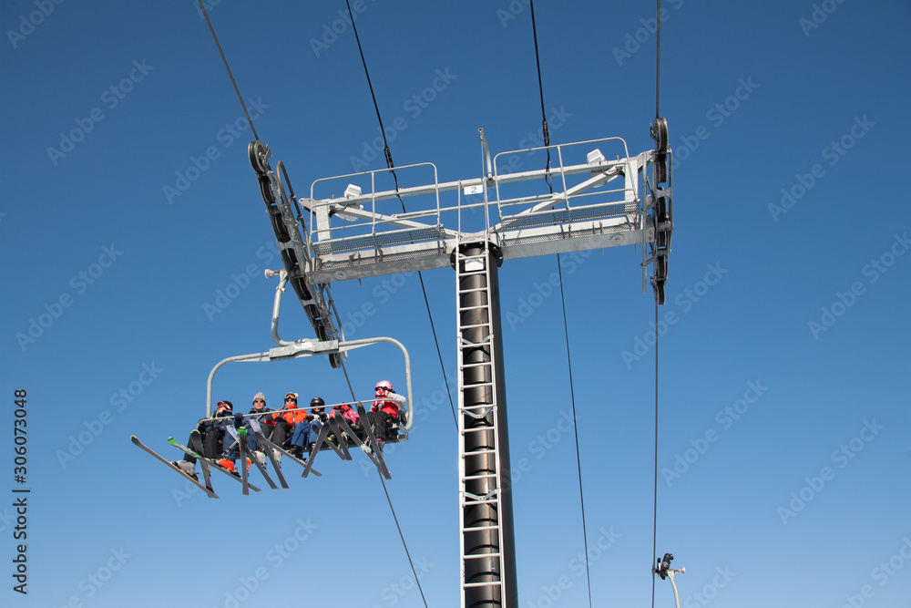 skiers and snowboarders are sitting on a ski cable chair lift