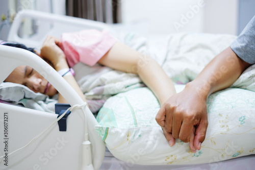 Hand of man hold hands with woman on the hospital bed.
