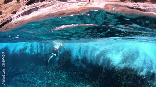 Man Snorkeling In Waves Beside A Cliff In Tropical Sea
