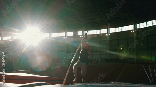 pole vaulting - young woman is running and jumping over the bar