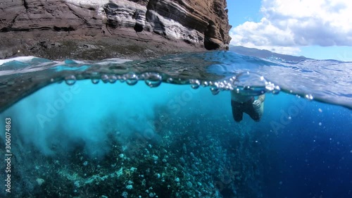 Man Swimming In Rough Tropical Sea Beside Coral Cliff