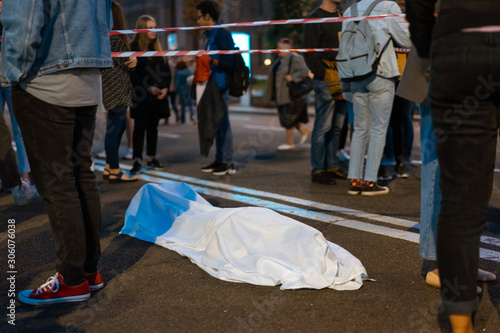 Human body covered by a sheet lying on the street.