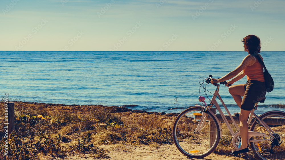 Obraz premium Woman ride bicycle on beach, active lifestyle.