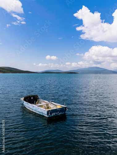 Small blue rowing boat moored in the sea, a cloudy sky