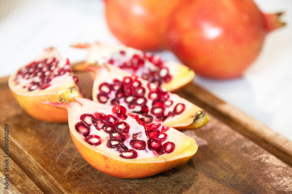 Pomegranate (Punica granatum) slice on wooden cutting board. Pomegranate (Punica granatum) slice on wooden cutting board.