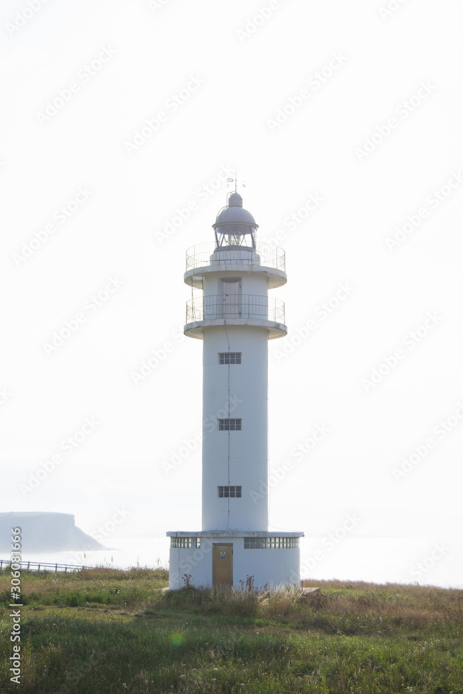 White beacon on coastline in daytime