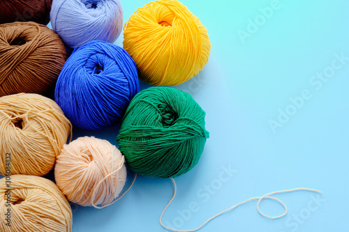 Mock-up made with bright color yarn clews on the blue background. Concept of amigurumi toy making, handicraft, knitting, hobbie. Can be used for posters