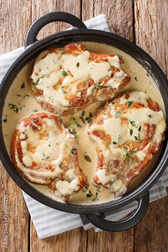 Cooked pork chops in creamy wine sauce with thyme close-up in a pan. Vertical top view