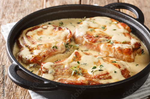 Delicious pork chops stewed in a creamy wine sauce with herbs close-up in a pan. horizontal