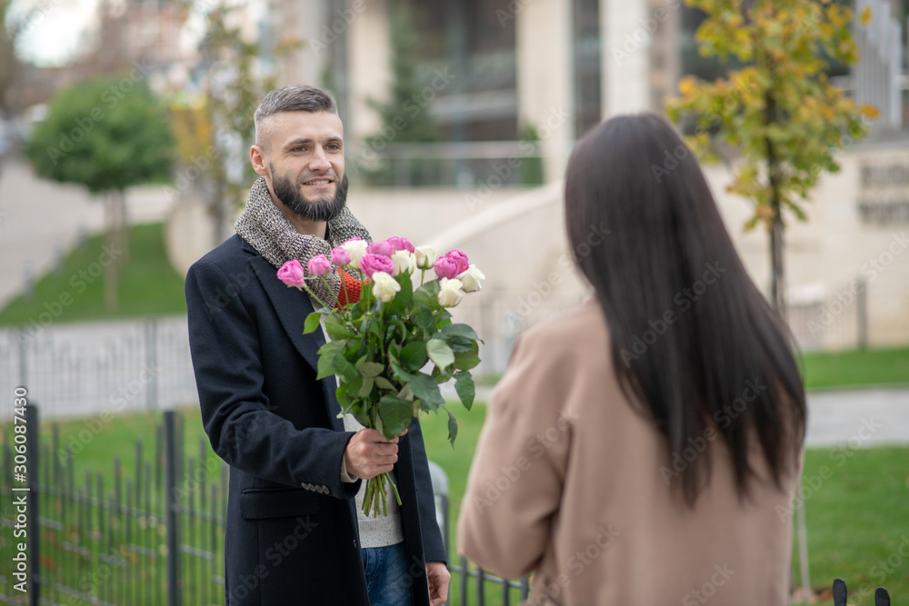 Bearded young man coming to a date with flowers Bearded young man coming to a date with flowers